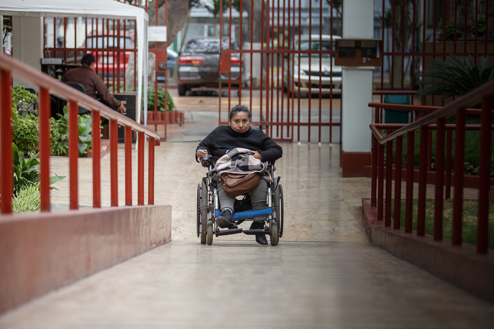 Una mujer adulta con discapacidad, usuaria de silla de ruedas, se desplaza y accede a un espacio utilizando una rampa.