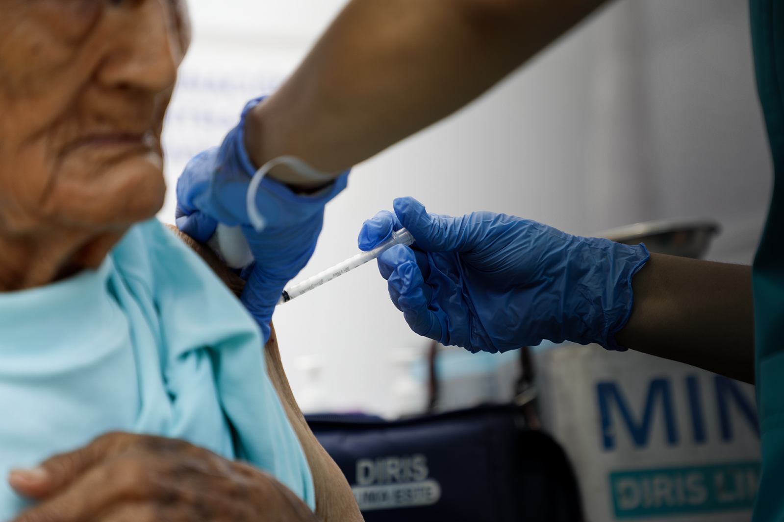 Una persona adulta mayor recibe una inyección en el brazo por parte de un profesional de la salud del Ministerio de Salud.