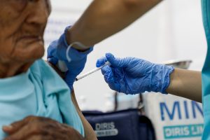 Una persona adulta mayor recibe una inyección en el brazo por parte de un profesional de la salud del Ministerio de Salud.