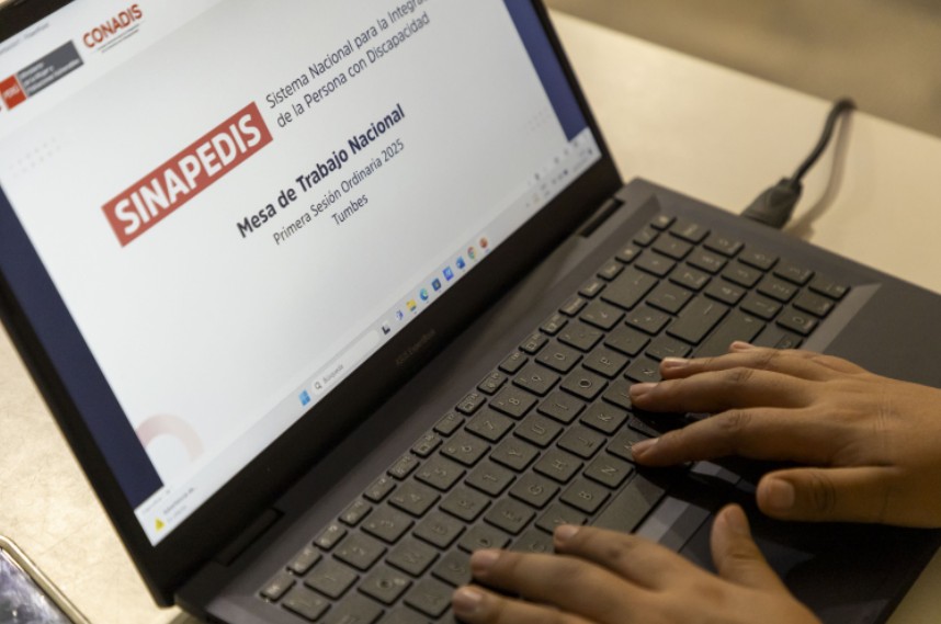 Una persona utiliza una computadora portátil con la presentación de la Mesa de Trabajo Nacional del SINAPEDIS abierta en la pantalla.