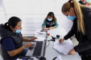 Un grupo de personas con mascarillas reunidas en una mesa revisando documentos