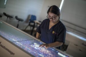 La imagen muestra a una mujer de mediana edad interactuando con algún tipo de tecnología.