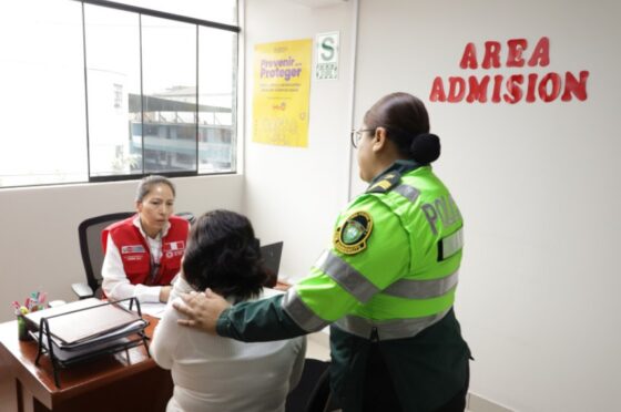 La imagen muestra a una funcionaria pública dando atención a una mujer acompañada de una policía.