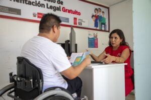 La imagen muestra a una persona en silla de ruedas en lo que parece una asesoría legal por parte de una servidora pública.