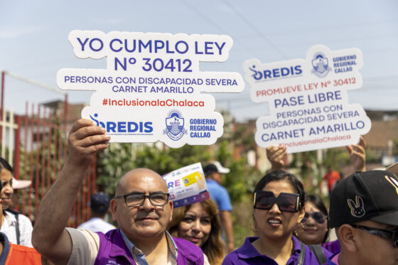 Personas vestidas con chalecos morados participan en un evento en la vía pública sosteniendo letreros blancos con forma de bocadillo o cartel. En el cartel principal en primer plano se lee: «Yo cumplo Ley N° 30412 - Personas con discapacidad severa, carnet amarillo #InclusiónalaChalaca», acompañado de los logos de OREDIS y el Gobierno Regional del Callao.
